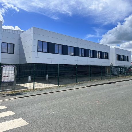 Vue extérieure des bureaux COMAT à Angers par SWEELCO, avec façades blanches et fenêtres sombres.