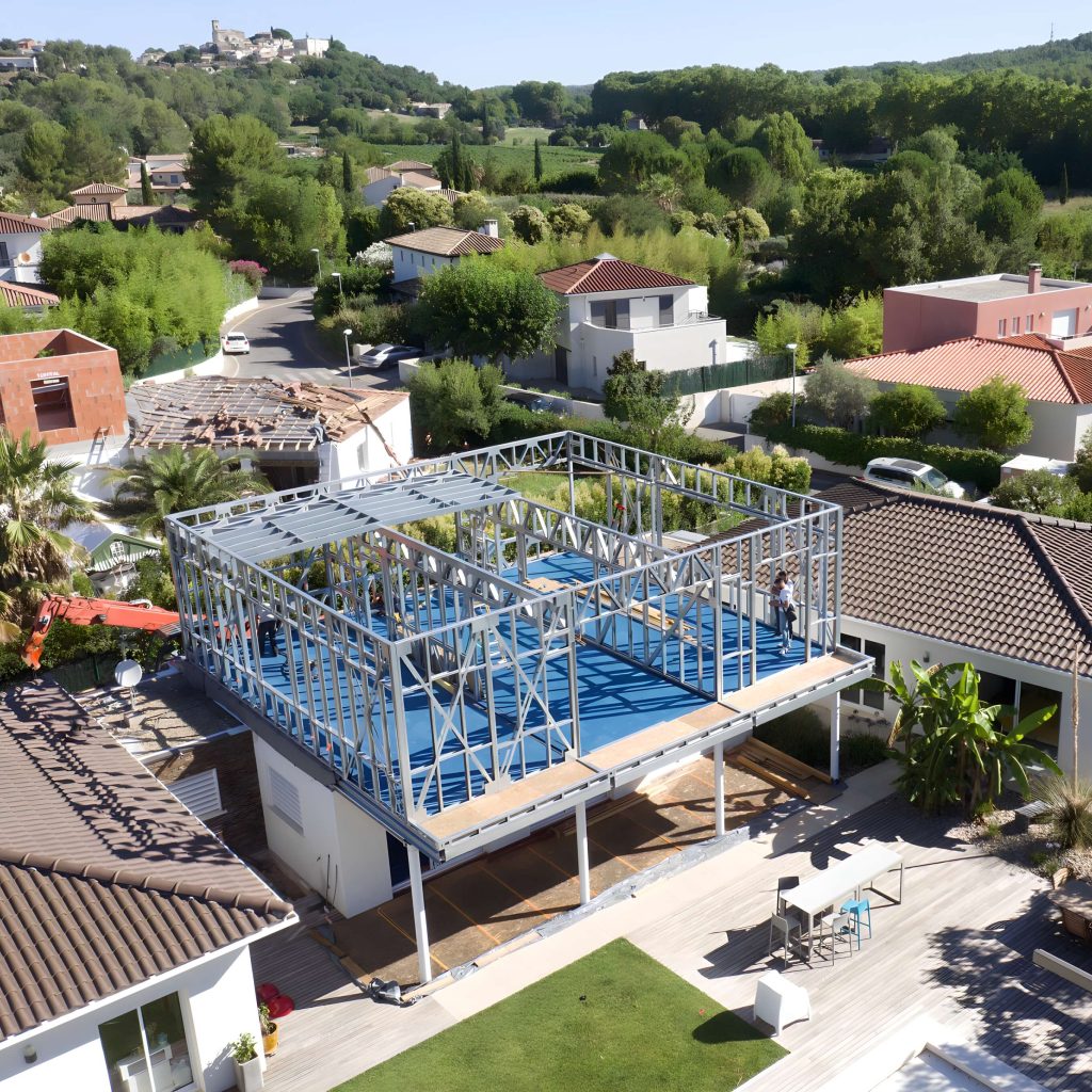 Vue aérienne de la maison individuelle à Montpellier pendant le montage de la surélévation par SWEELCO, avec structure métallique visible.
