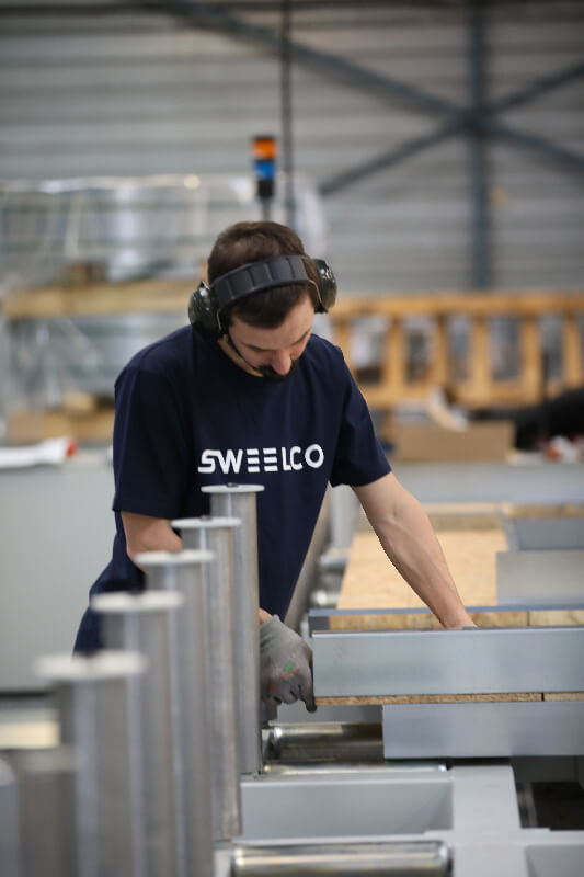 Opérateur de production de SWEELCO travaillant dans l'atelier avec des équipements de protection auditive.