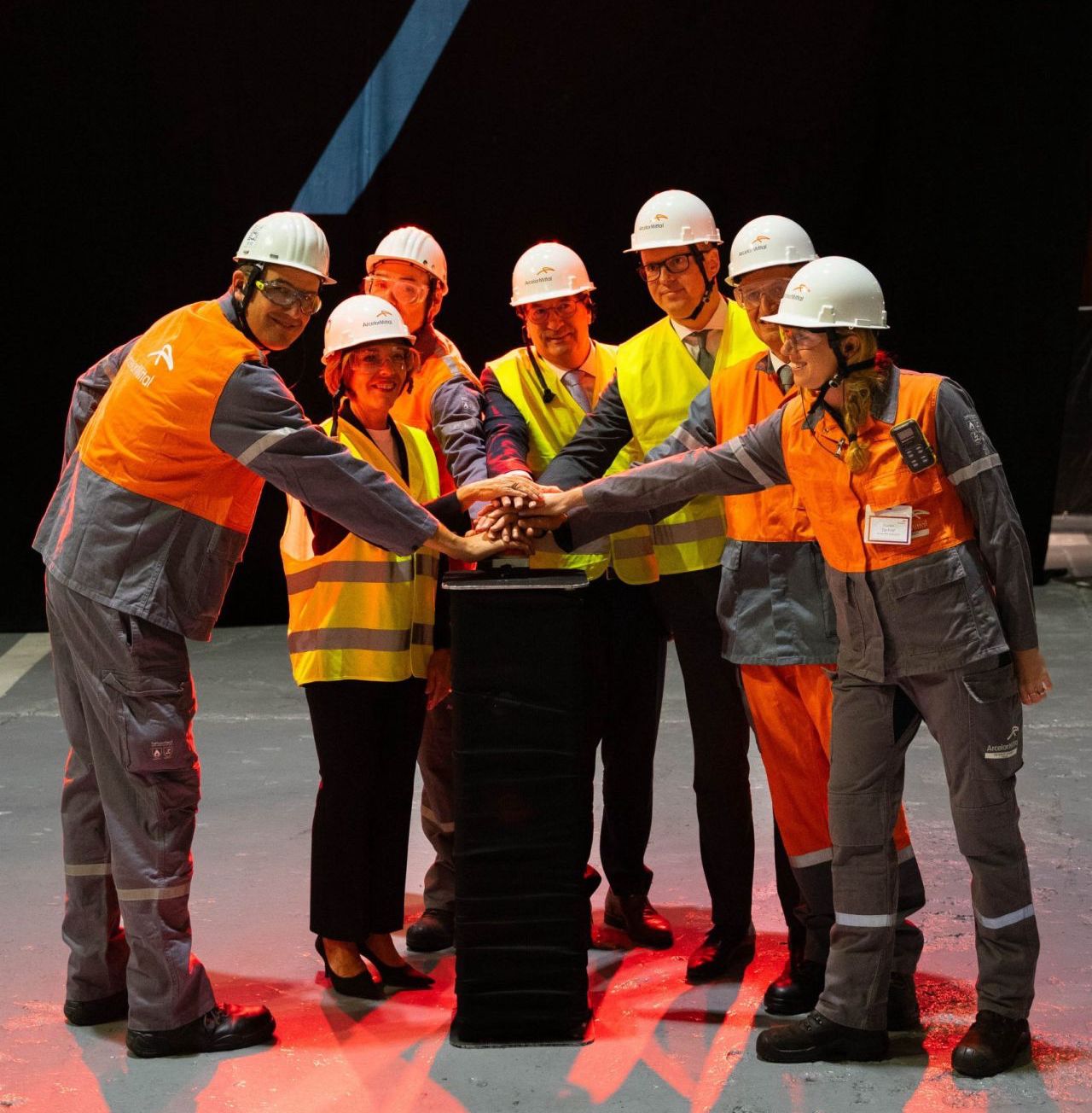 Cérémonie d'inauguration avec des employés et responsables en gilets de sécurité et casques chez ArcelorMittal.